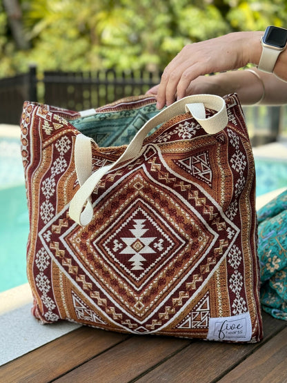 Woman uses woven Desert Night tote bag - rich shades of browns and earthy tones. Made from recycled materials