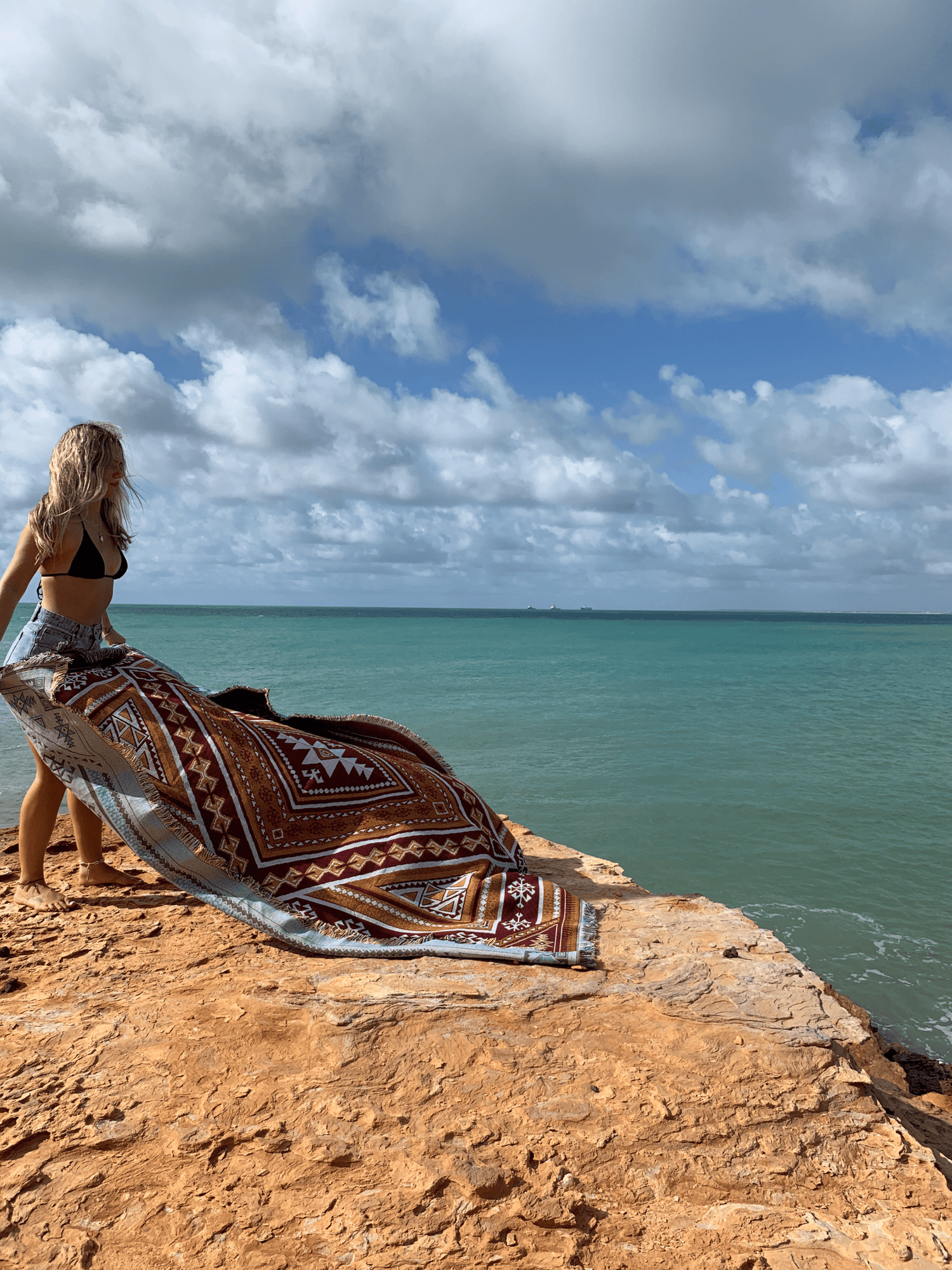 Desert Night throw being laid out on a rocks edge overlooking the ocean in Western Australia