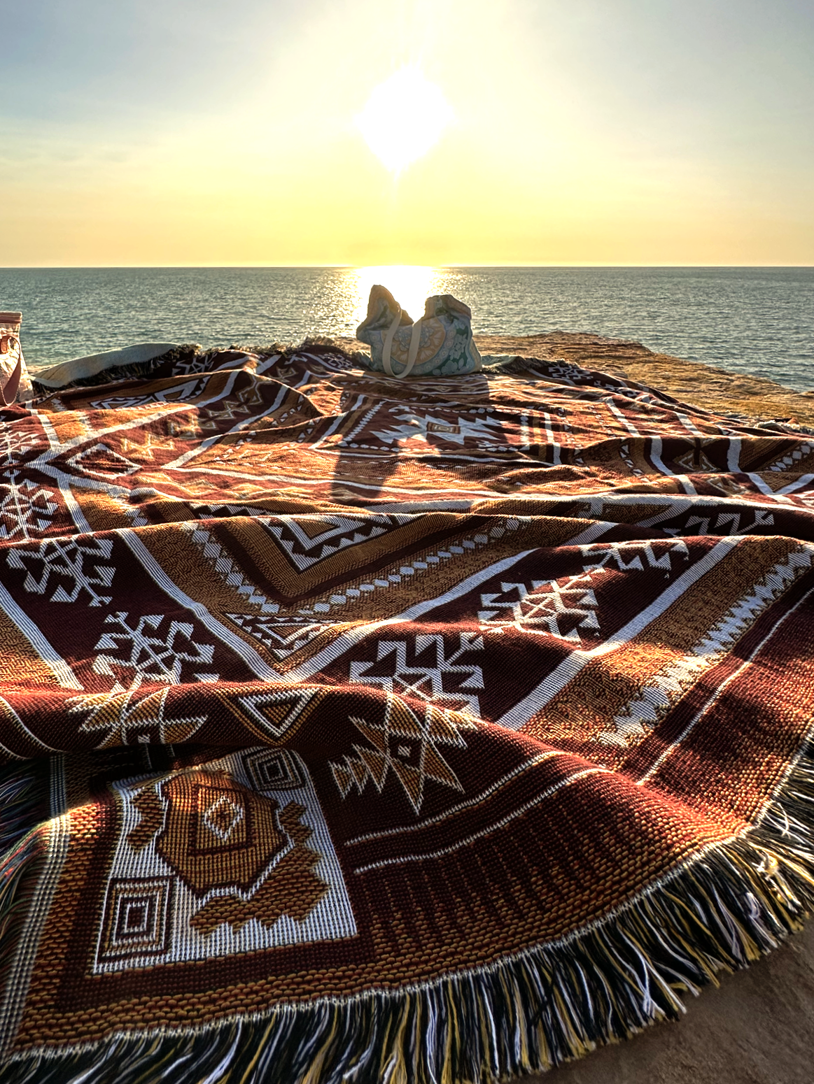 Desert Night throw rug and picnic blanket watching sunset over the ocean. Shades of brown, boho rug, must-have van life accessory. Designed in Australia for adventure.