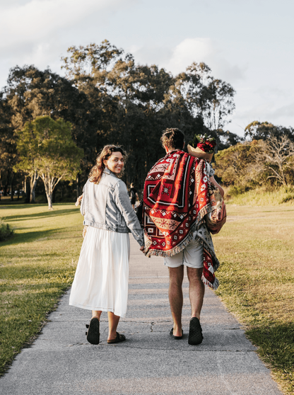 Couple on a picnic date with red picnic blanket / throw rug. Valentines picnic idea
