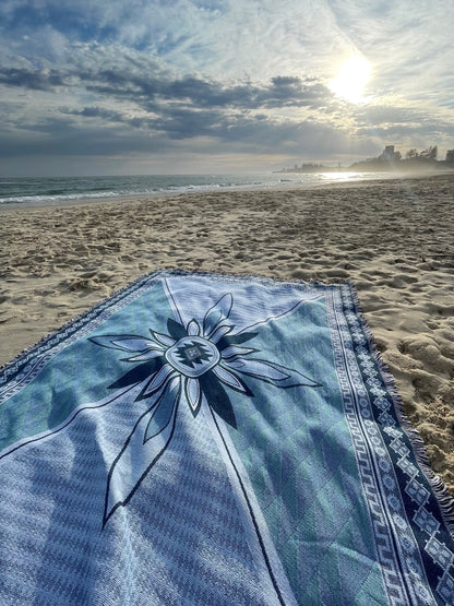 Shooting Stars blue throw rug, picnic blanket laying on sand overlooking sunrise and the ocean on the Gold Coast. Designed in Aus.