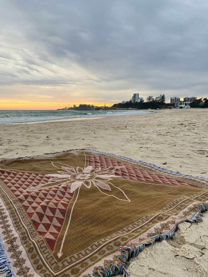 Reverse side of Shooting Stars blue throw rug, picnic blanket laying on beach overlooking sunset on Gold Coast. Designed in Aus.
