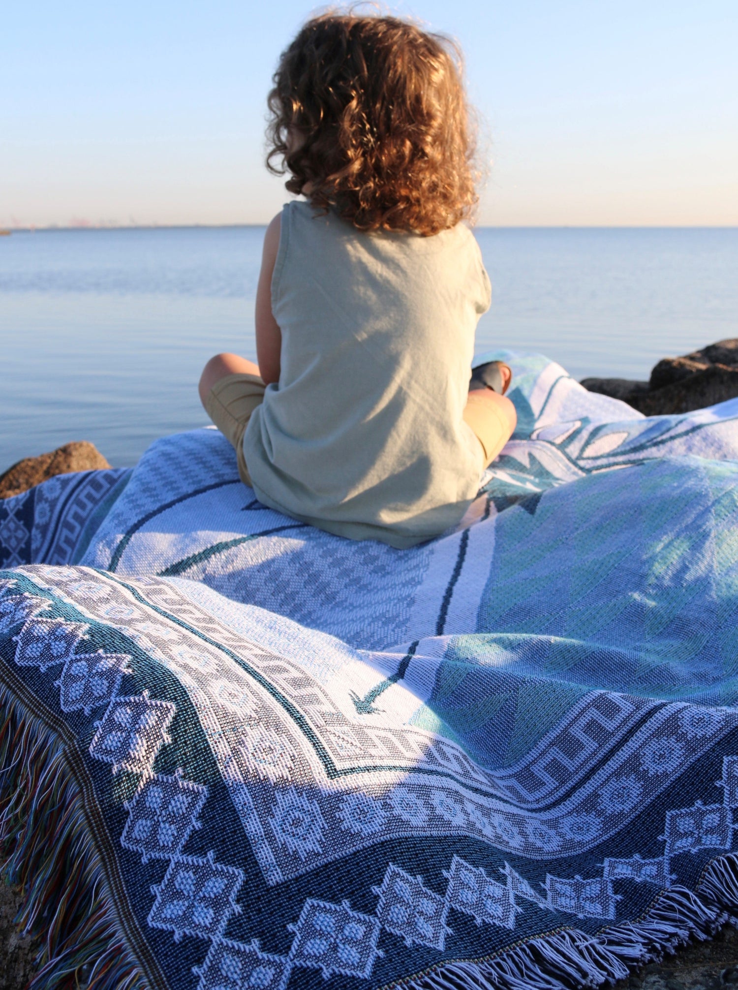 Shooting Stars blue throw rug, picnic blanket laying on rocks overlooking ocean. Quality family time. Designed in Aus.